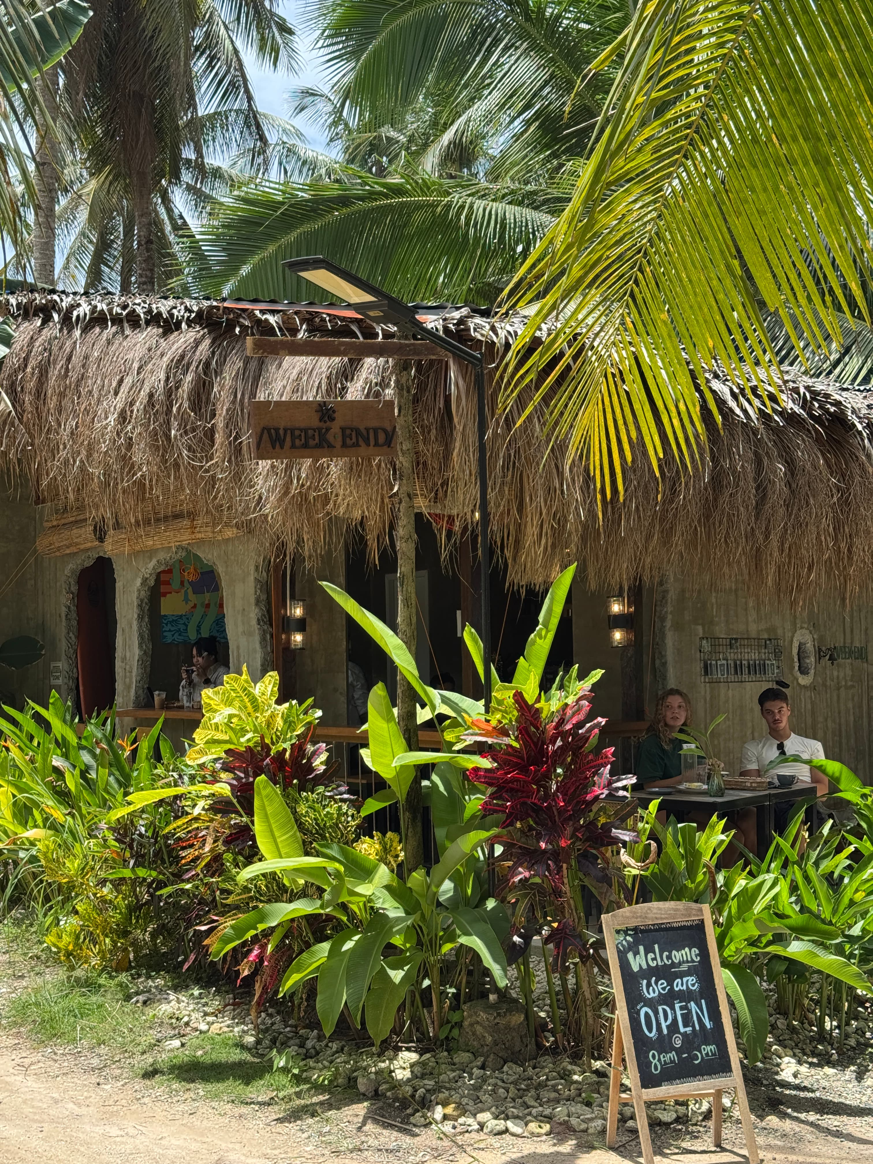 Weekend Cafe exterior with thatched roof and tropical plants in Siargao